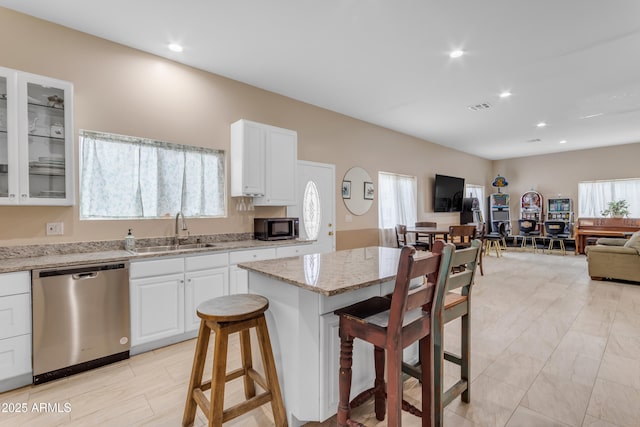 kitchen featuring appliances with stainless steel finishes, white cabinetry, sink, a kitchen bar, and light stone counters