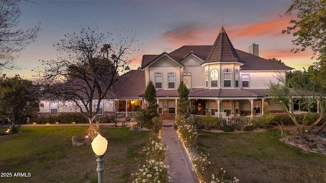 victorian-style house featuring a yard and covered porch