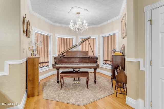 miscellaneous room with crown molding, a notable chandelier, hardwood / wood-style flooring, and a textured ceiling