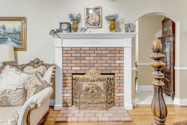 sitting room featuring a brick fireplace and wood-type flooring