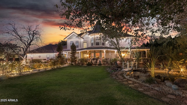 back house at dusk featuring a lawn