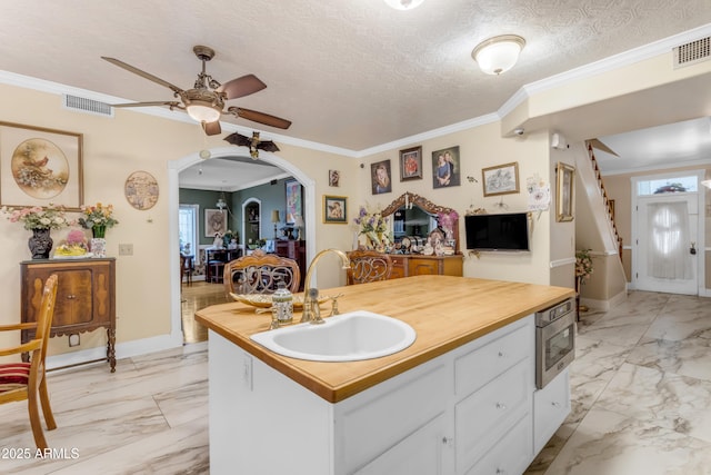 kitchen featuring white cabinetry, sink, crown molding, and a textured ceiling