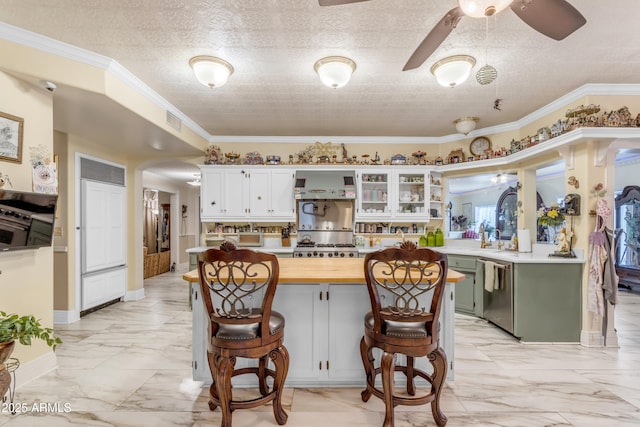 kitchen with a breakfast bar area, ornamental molding, green cabinets, a kitchen island, and stainless steel appliances