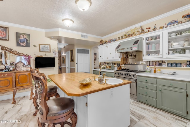 kitchen with white cabinetry, a kitchen island, wall chimney range hood, and stainless steel range