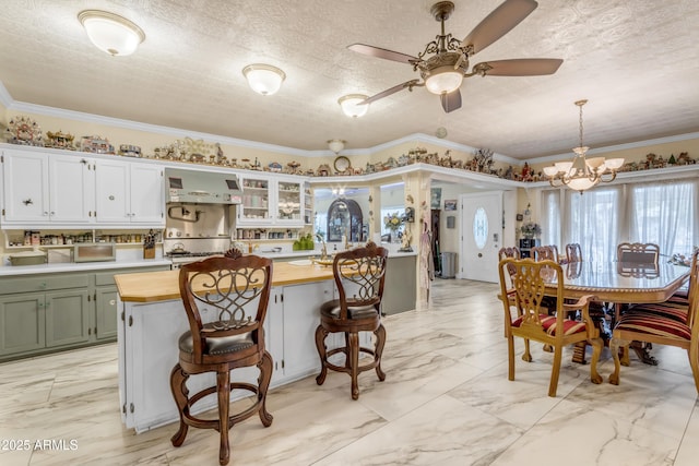 kitchen featuring pendant lighting, white cabinetry, butcher block countertops, and a breakfast bar area