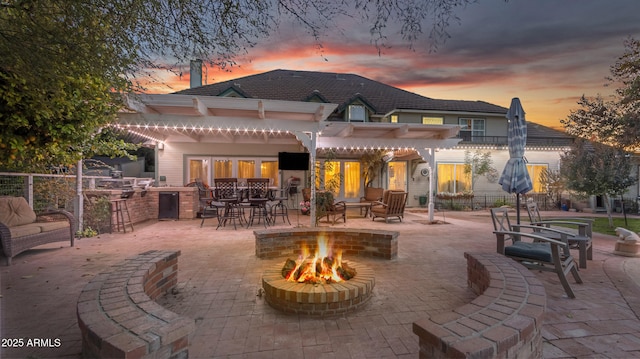 back of property with a pergola, an outdoor fire pit, a patio area, area for grilling, and a bar