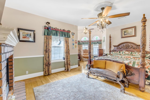 bedroom featuring ceiling fan, a fireplace, and hardwood / wood-style floors