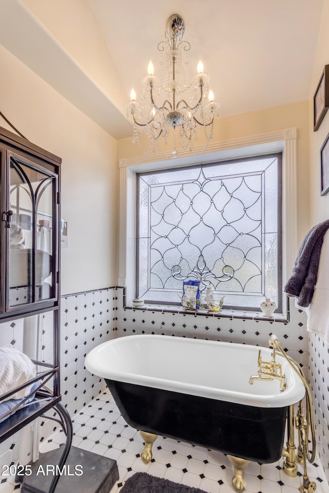 bathroom featuring tile walls, a tub to relax in, a notable chandelier, and plenty of natural light