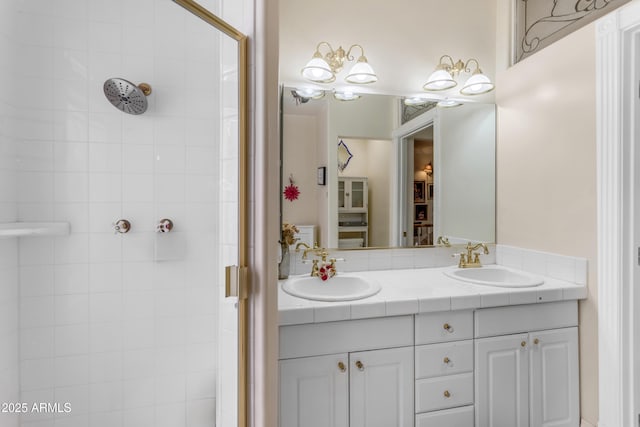 bathroom featuring tiled shower and vanity