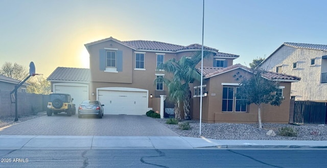 view of front of house featuring a tile roof, fence, decorative driveway, and stucco siding