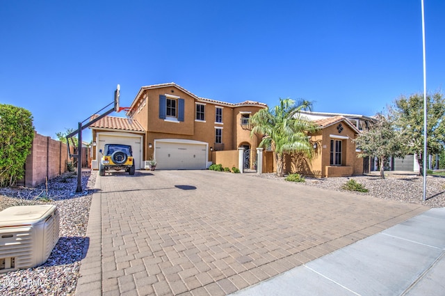 view of front of home with fence, an attached garage, stucco siding, a tiled roof, and decorative driveway