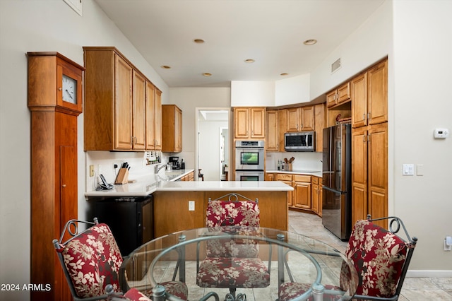 kitchen with light tile patterned floors, sink, appliances with stainless steel finishes, and kitchen peninsula