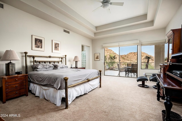 bedroom with access to exterior, ceiling fan, a tray ceiling, and carpet flooring