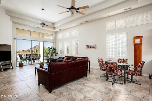 living room featuring a healthy amount of sunlight, ceiling fan, and a towering ceiling