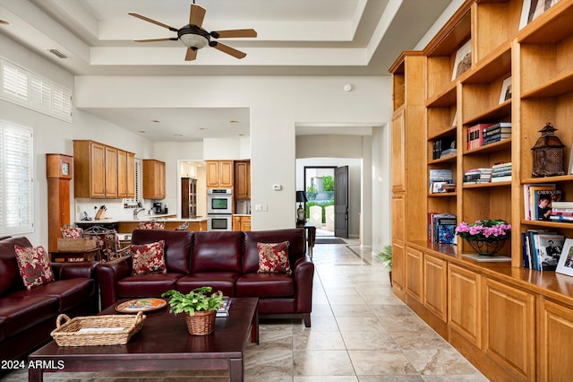 tiled living room featuring a raised ceiling and ceiling fan