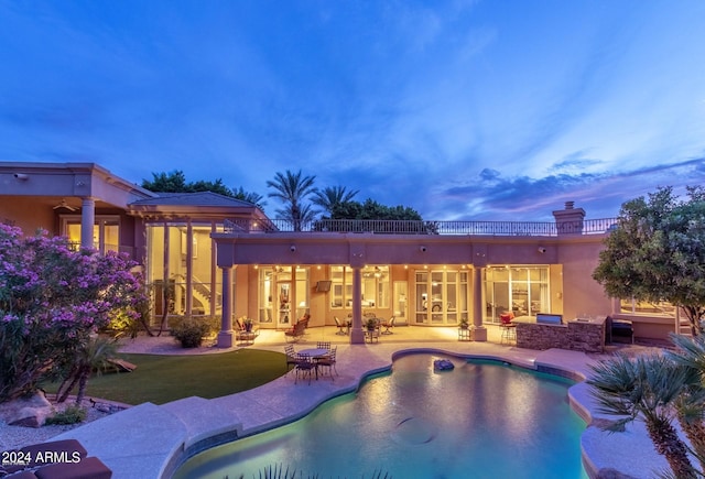 pool at dusk with a patio, a lawn, and ceiling fan