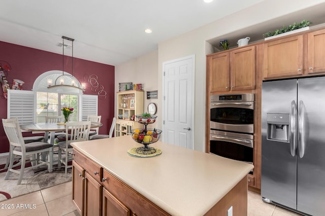 kitchen with a chandelier, a center island, hanging light fixtures, light tile patterned floors, and appliances with stainless steel finishes