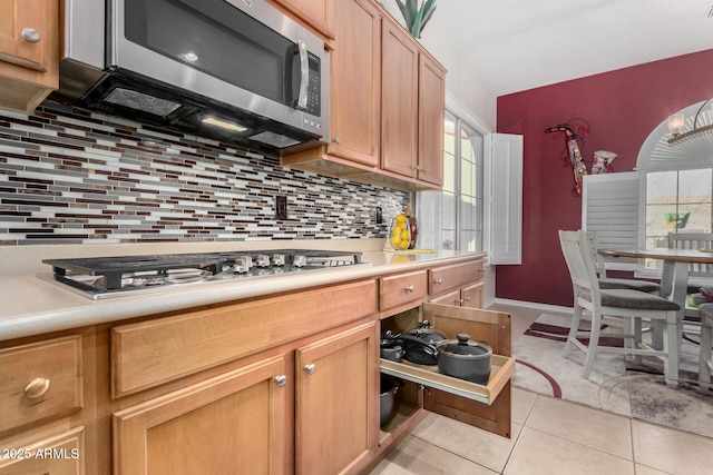 kitchen featuring stainless steel appliances, light tile patterned flooring, and backsplash