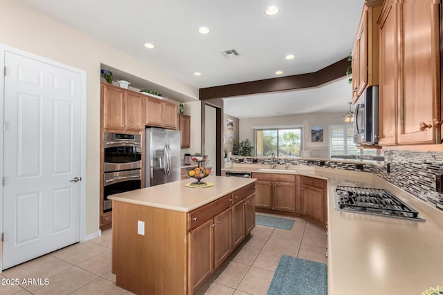 kitchen with sink, light tile patterned floors, stainless steel appliances, a center island, and tasteful backsplash