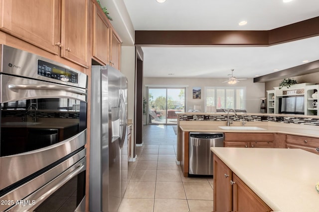 kitchen featuring sink, light tile patterned floors, ceiling fan, kitchen peninsula, and stainless steel appliances