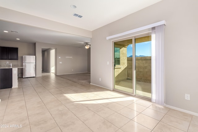 spare room featuring ceiling fan, sink, and light tile patterned floors