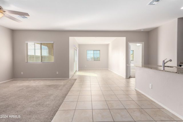 unfurnished room with sink, light carpet, and ceiling fan