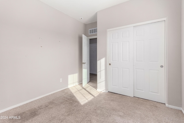 unfurnished bedroom featuring light carpet and a closet