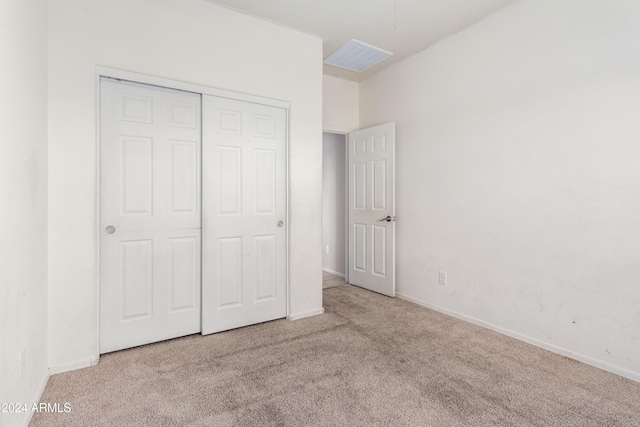 unfurnished bedroom with a closet and light colored carpet