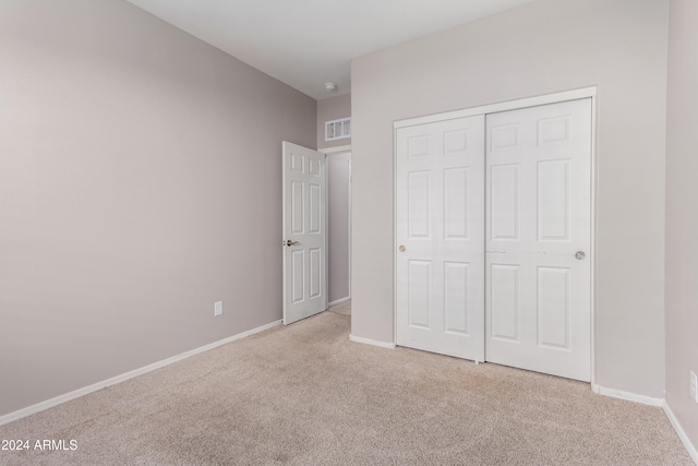 unfurnished bedroom featuring a closet and light colored carpet