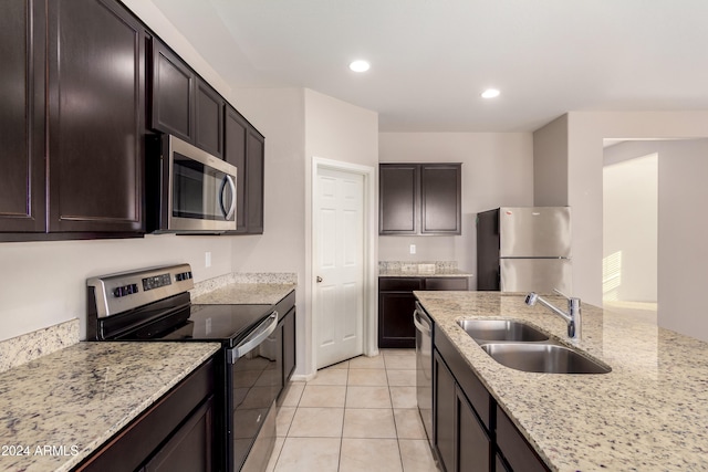 kitchen with dark brown cabinetry, sink, light tile patterned flooring, light stone countertops, and appliances with stainless steel finishes