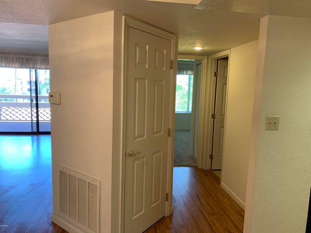 hallway with a textured ceiling and dark wood-type flooring