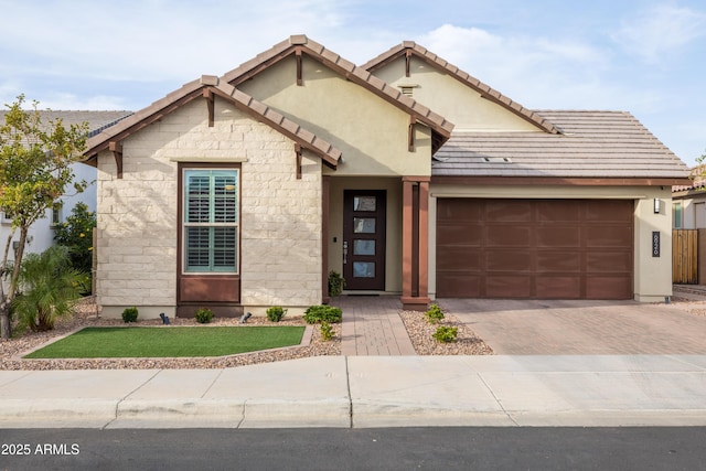 view of front of house featuring a garage, stucco siding, decorative driveway, and a tiled roof