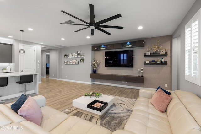 living room featuring visible vents, baseboards, a ceiling fan, light wood-style floors, and recessed lighting