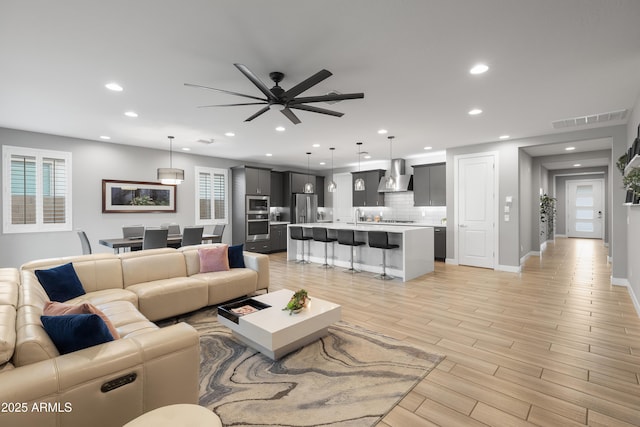 living area featuring ceiling fan, light wood-style floors, visible vents, and recessed lighting