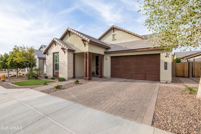 view of front of property with a garage, decorative driveway, fence, and stucco siding