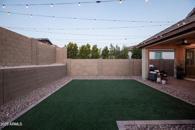 view of yard with a ceiling fan, a fenced backyard, and a patio