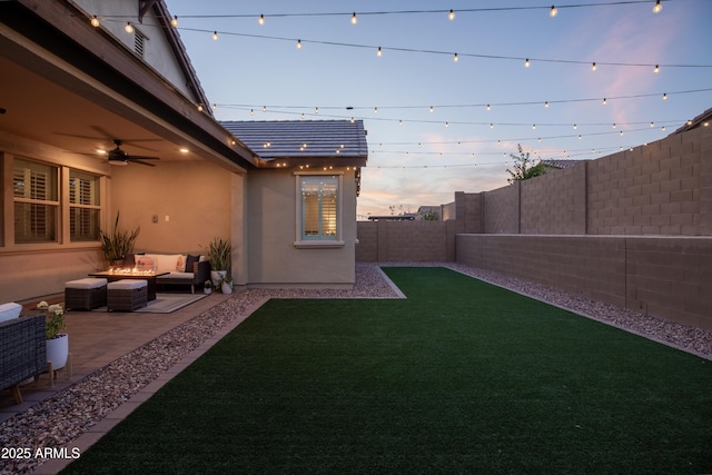 yard at dusk featuring a ceiling fan, a patio area, outdoor lounge area, and a fenced backyard