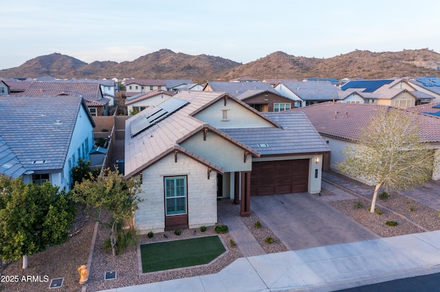 view of front of house with a residential view, decorative driveway, a mountain view, and an attached garage