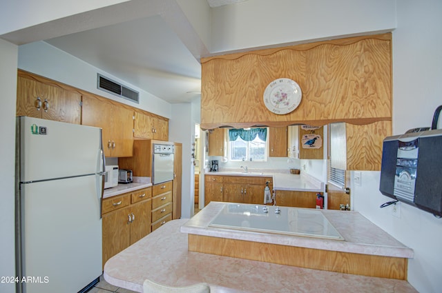 kitchen featuring white appliances, kitchen peninsula, and light tile patterned floors