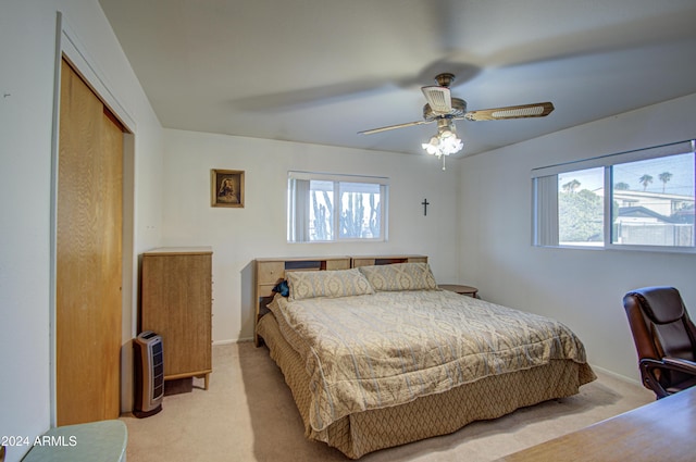 carpeted bedroom featuring multiple windows, ceiling fan, and a closet