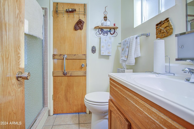 bathroom with tile patterned flooring, vanity, toilet, and walk in shower