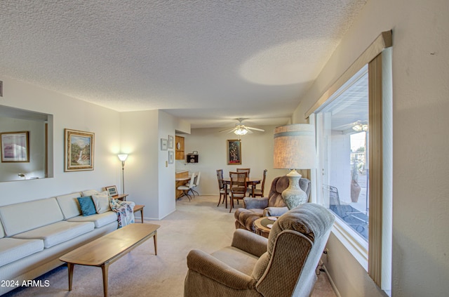 living room with a textured ceiling, light colored carpet, and ceiling fan