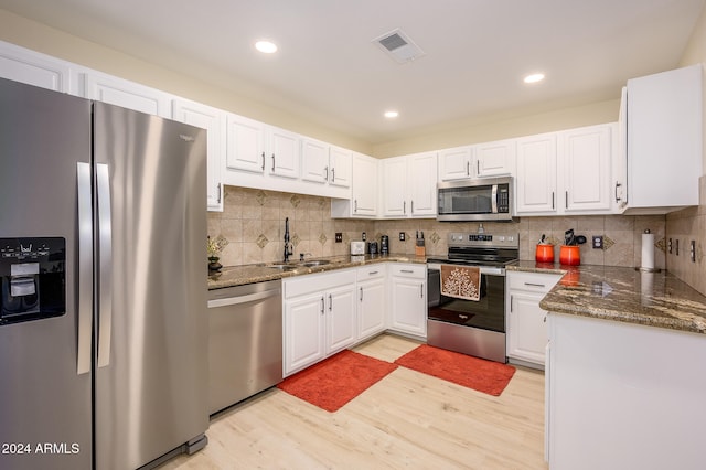 kitchen featuring light hardwood / wood-style flooring, sink, stainless steel appliances, backsplash, and white cabinetry