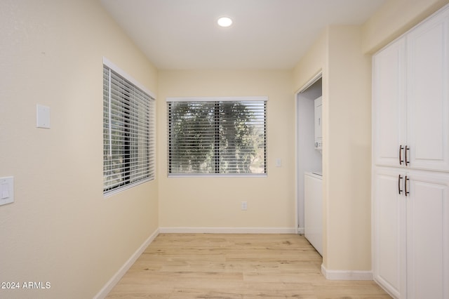 hallway with light hardwood / wood-style floors and stacked washer / drying machine