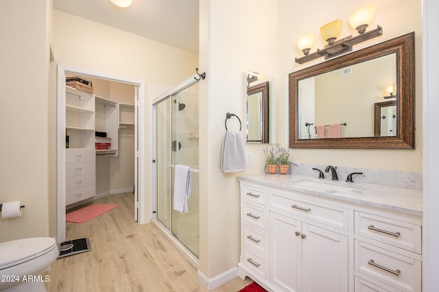 bathroom featuring vanity, toilet, hardwood / wood-style floors, and a shower with door