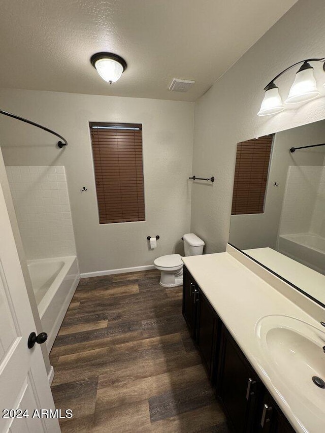 full bathroom featuring vanity, shower / washtub combination, toilet, a textured ceiling, and wood-type flooring