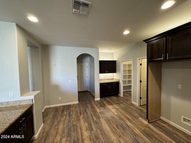 kitchen with dark brown cabinets, light stone countertops, and dark wood-type flooring