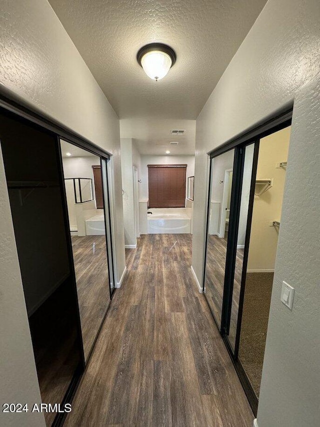 hallway featuring a textured ceiling and dark hardwood / wood-style flooring