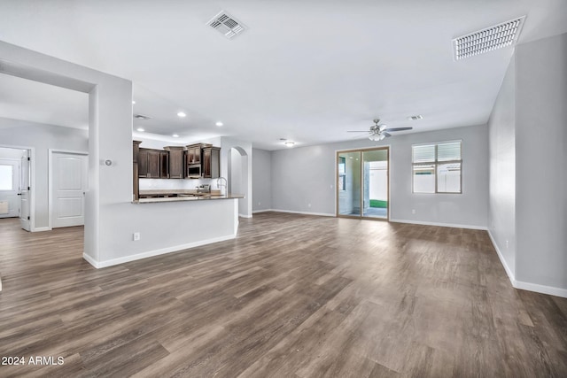 unfurnished living room with ceiling fan, sink, and dark wood-type flooring