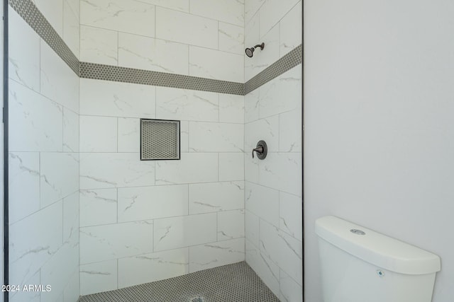 bathroom featuring a tile shower and toilet